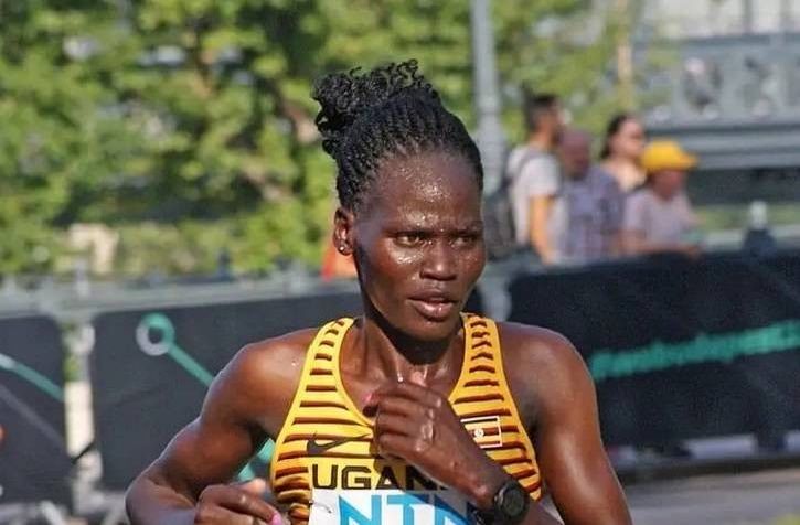 Rebecca Cheptegei court un marathon avec un maillot rayé jaune et noir de l'équipe d'athlétisme de l'Ouganda.