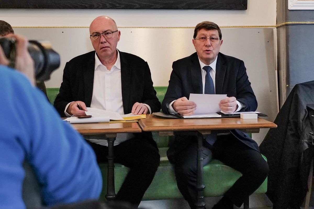 Conférence de presse à Genève pour le lancement de l’initiative du MCG, avec Mauro Poggia et François Baertschi assis à une table.