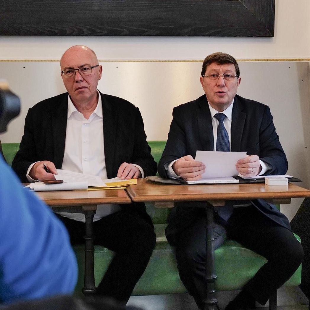 Conférence de presse à Genève pour le lancement de l’initiative du MCG, avec Mauro Poggia et François Baertschi assis à une table.
