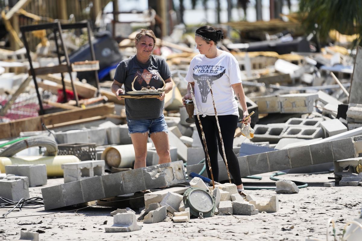 Deux femmes récupèrent des biens parmi les débris d'une maison détruite à Horseshoe Beach, en Floride, après l'ouragan Helene, le samedi 28 septembre 2024.