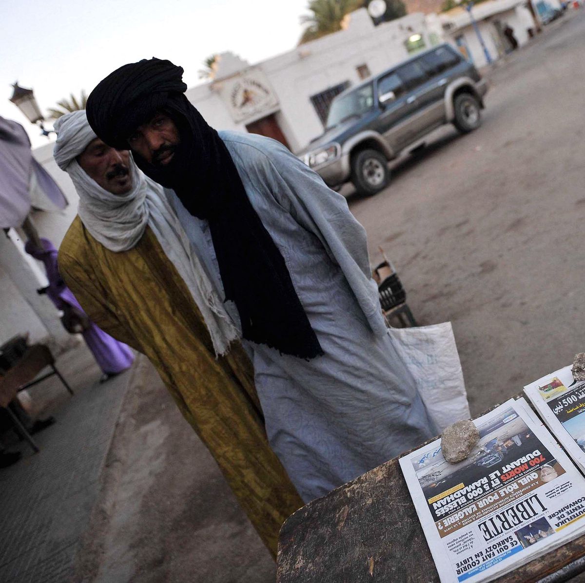 Des hommes se tiennent à côté de journaux à Djanet.
