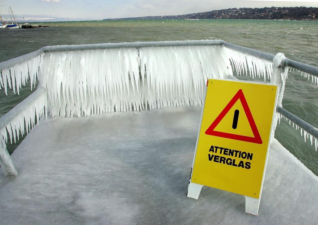Un panneau avertis sur le risque de verglas sur les quais tandis que derriere la formation de glace due au froid et aux embruns donne des sculptures original, ce lundi 28 fevrier 2005 a Geneve. Un front froid accompagne d' une forte bise a provoque des chutes de neige et une baisse des temperatures dans la nuit de dimanche a lundi. Verglas et congeres ont perturbe le trafic, notamment sur l' Arc lemanique. (KEYSTONE/Martial Trezzini)