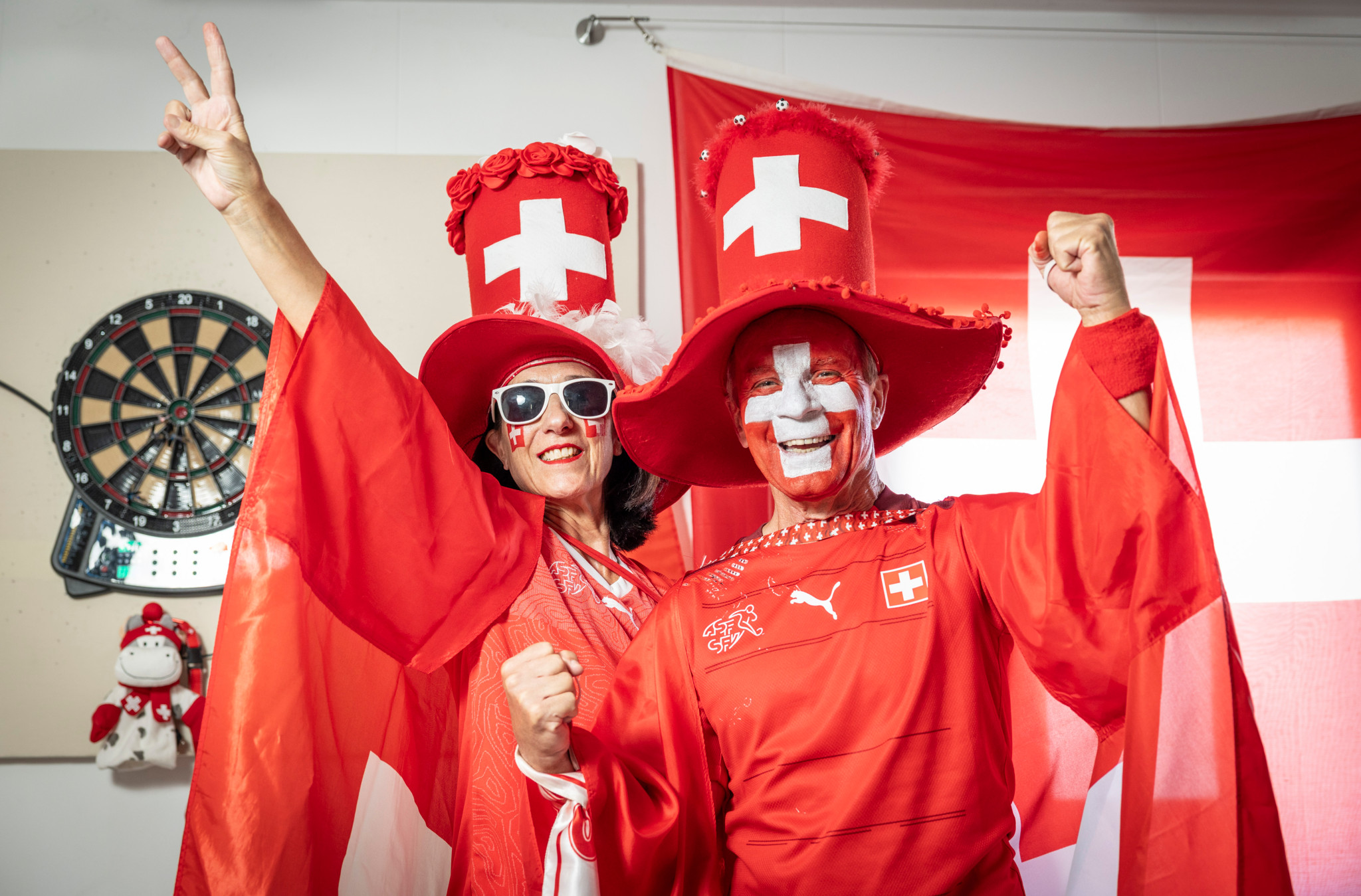 Karl und Doris Gorsatt in rot-weissen Schweizer Fan-Outfits mit bemalten Gesichtern und Schweizer Fahnen feiern zuhause die WM. Karl und Doris Gorsatt in rot-weissen Schweizer Fan-Outfits mit bemalten Gesichtern und Schweizer Fahnen feiern zuhause die WM.