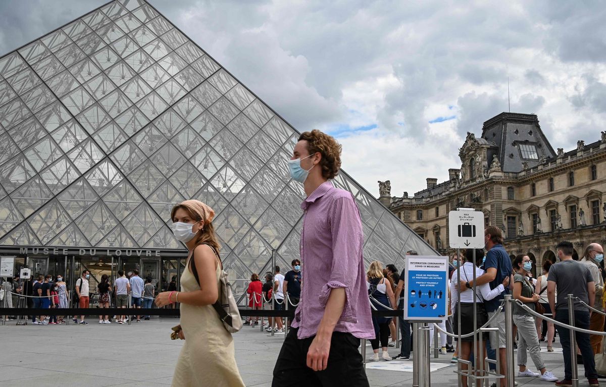 Des touristes font la queue masqués pour visiter le Louvre, à Paris.