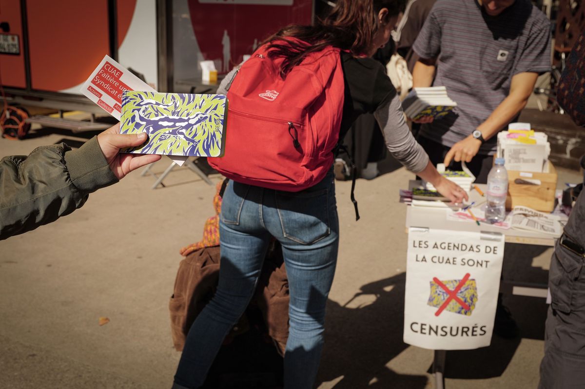 Étudiants au parvis de l'Uni Mail à Genève le 16 septembre 2024, distribuant des agendas de la CUAE. Une affiche indique 'Les agendas de la CUAE sont censurés'.