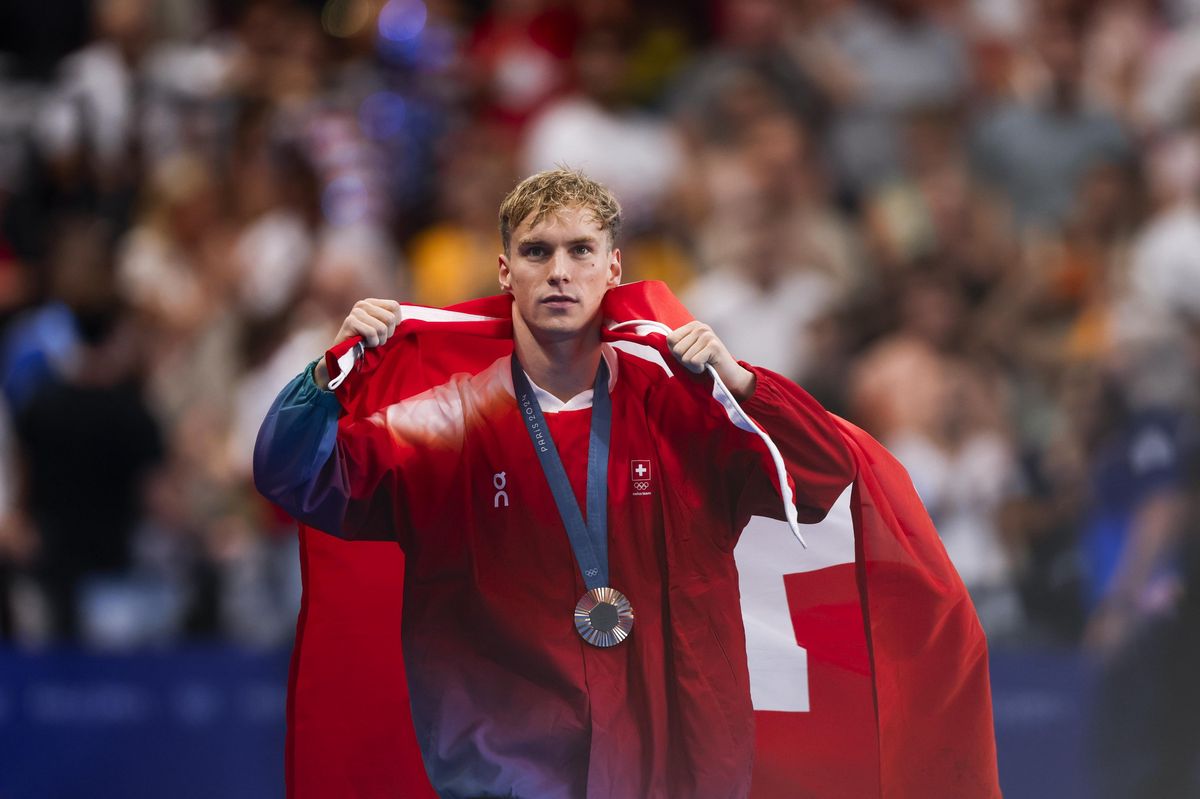 Roman Mityukov avec sa médaille de bronze et le drapeau suisse après la finale du 200m dos aux Jeux olympiques de Paris 2024.