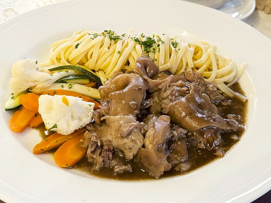 Assiette de spaghettis, légumes et morceaux de viande en sauce.