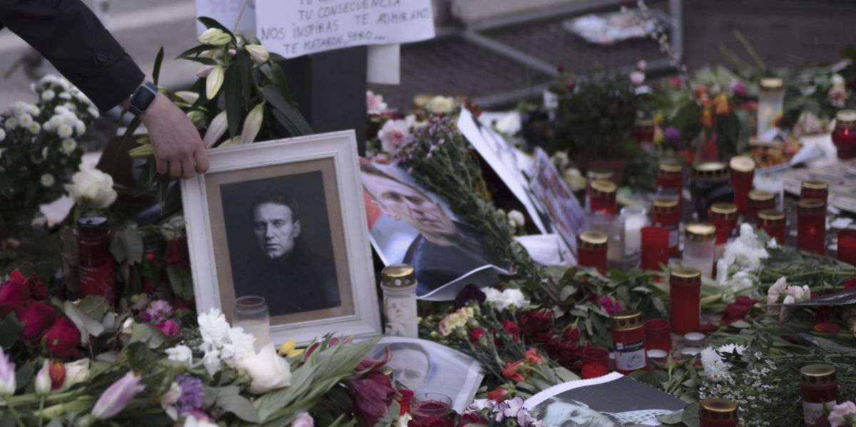 A man places a photo of Russian opposition leader Alexei Navalny between flowers and candles near the Russian emabssy, during a protest in Berlin, Sunday, Feb. 18, 2024. Navalny, who crusaded against official corruption and staged massive anti-Kremlin protests as President Vladimir Putin's fiercest foe, died Friday, aged 47, in the Arctic penal colony where he was serving a 19-year sentence, Russia's prison agency said. (AP Photo/Markus Schreiber)