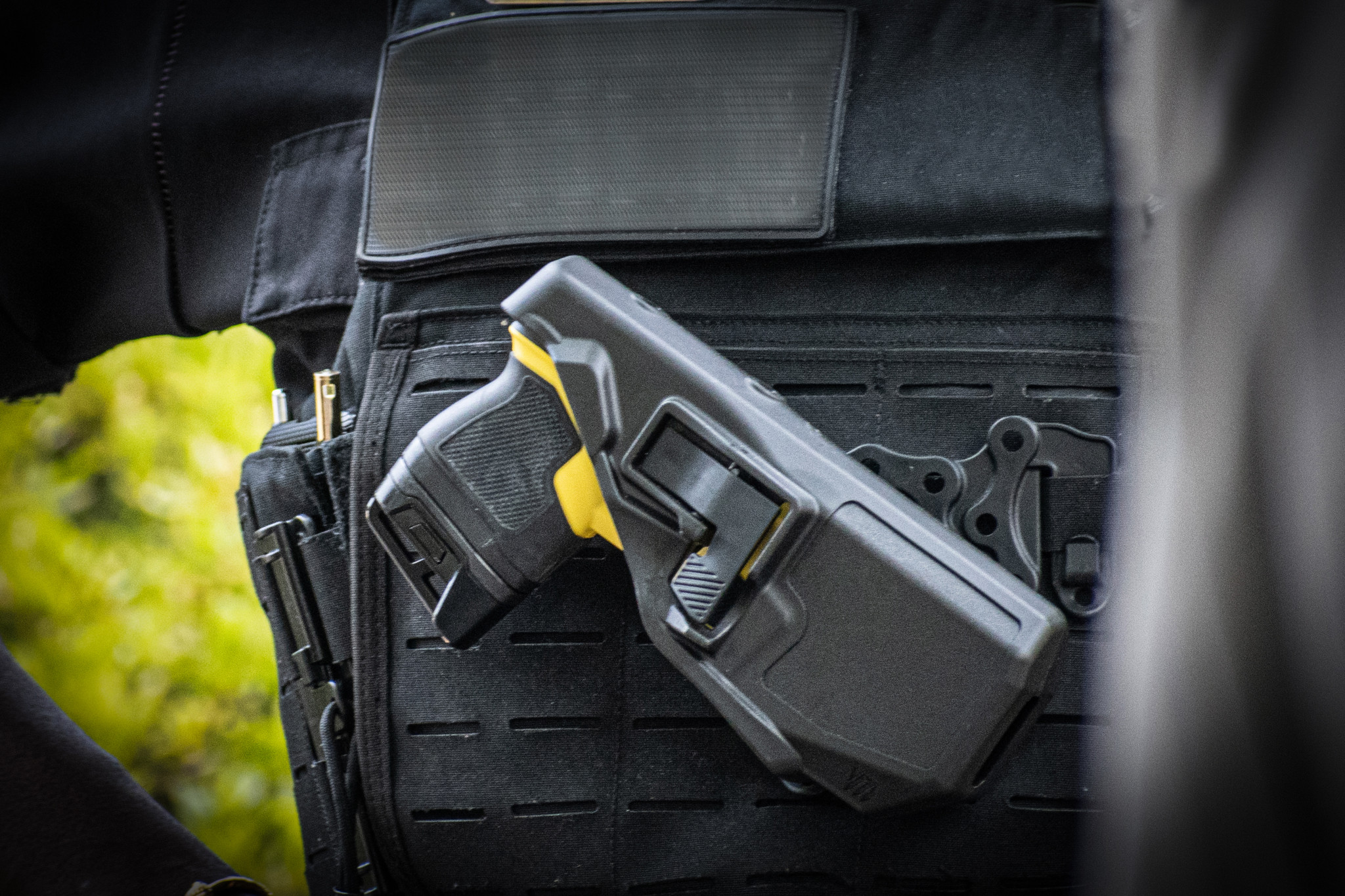Polizeiwaffe Taser in Holster an einer Schutzweste befestigt.