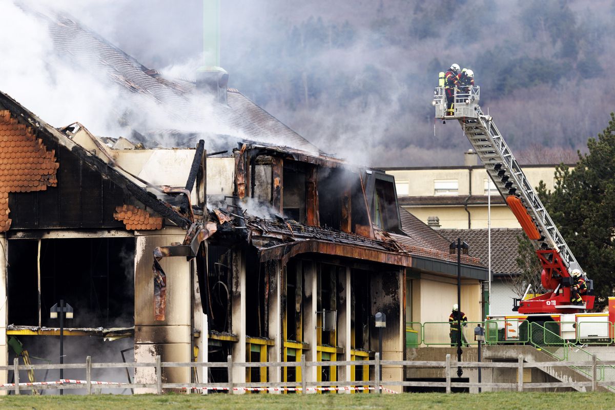 Des pompiers s'affairent a eteindre l'incendie dans les decombres du batiment de l'ecole ce mercredi 21 fevrier 2024 a Biere. Un important incendie ravage le college de Biere (VD) depuis mercredi matin. L'ntervention rapide des pompiers a toutefois permis de circonscrire le sinistre au niveau de la salle de gymnastique, ou s'est déclare le feu.(KEYSTONE/Valentin Flauraud)