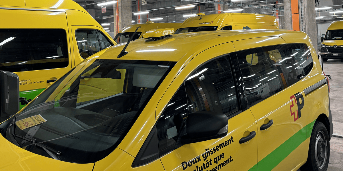 Véhicules de livraison jaunes et verts de La Poste, garés dans un garage souterrain.