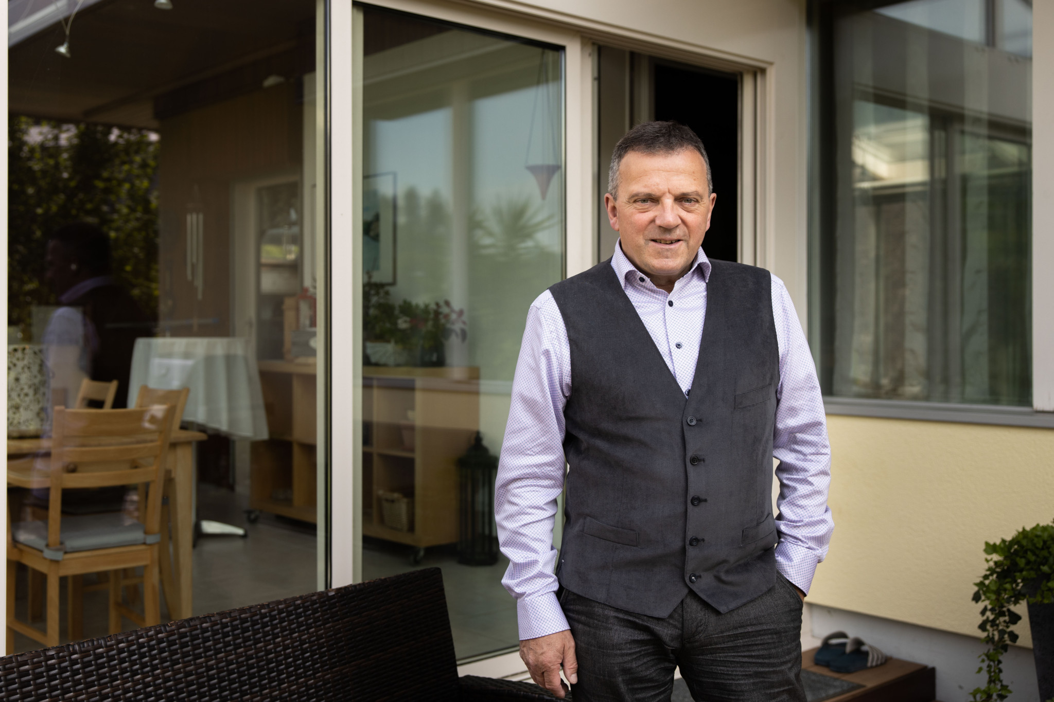 Walter Wobmann, SVP-Politiker aus Solothurn, steht vor einem Gebäude mit Glasschiebetür und Terrasse.