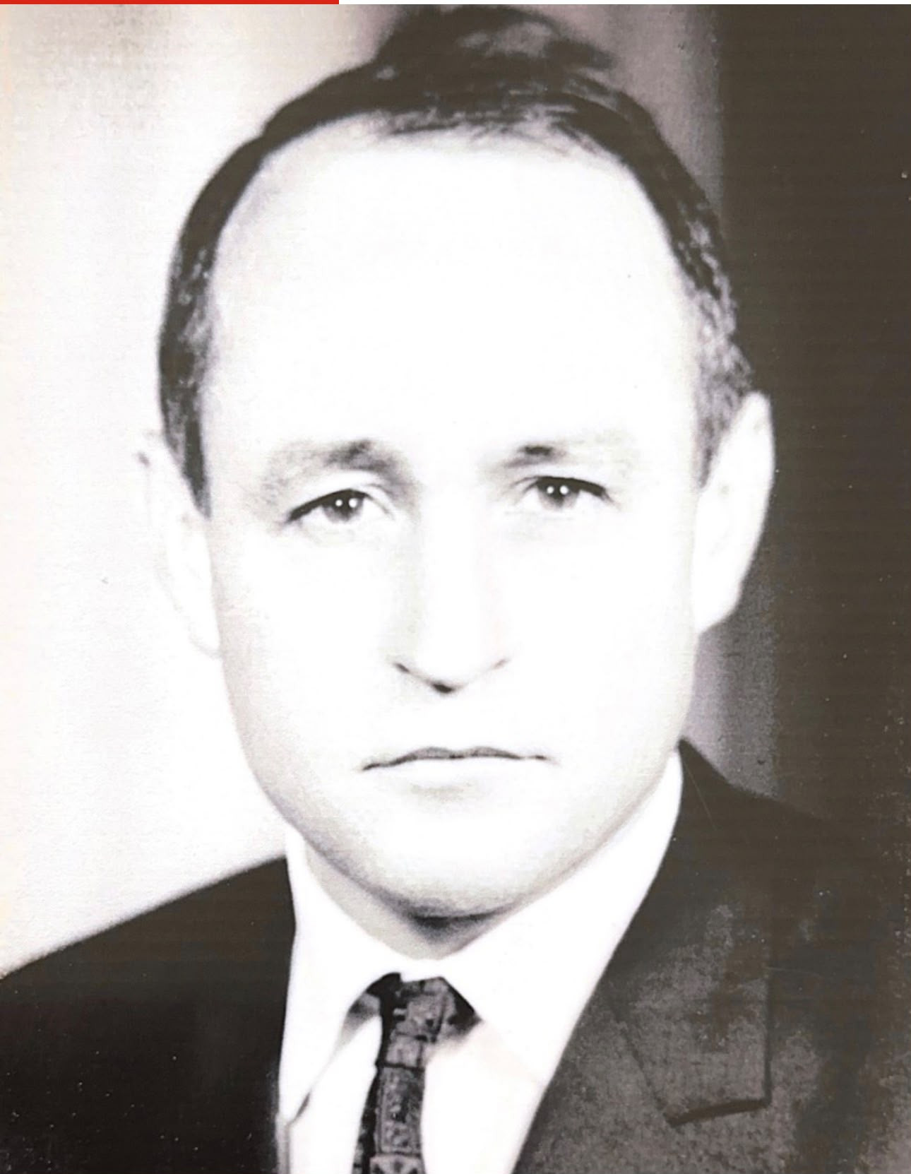 Portrait en noir et blanc d&rsquo;un homme en costume et cravate, regard s&eacute;rieux, style photographique des ann&eacute;es 1960-1970.