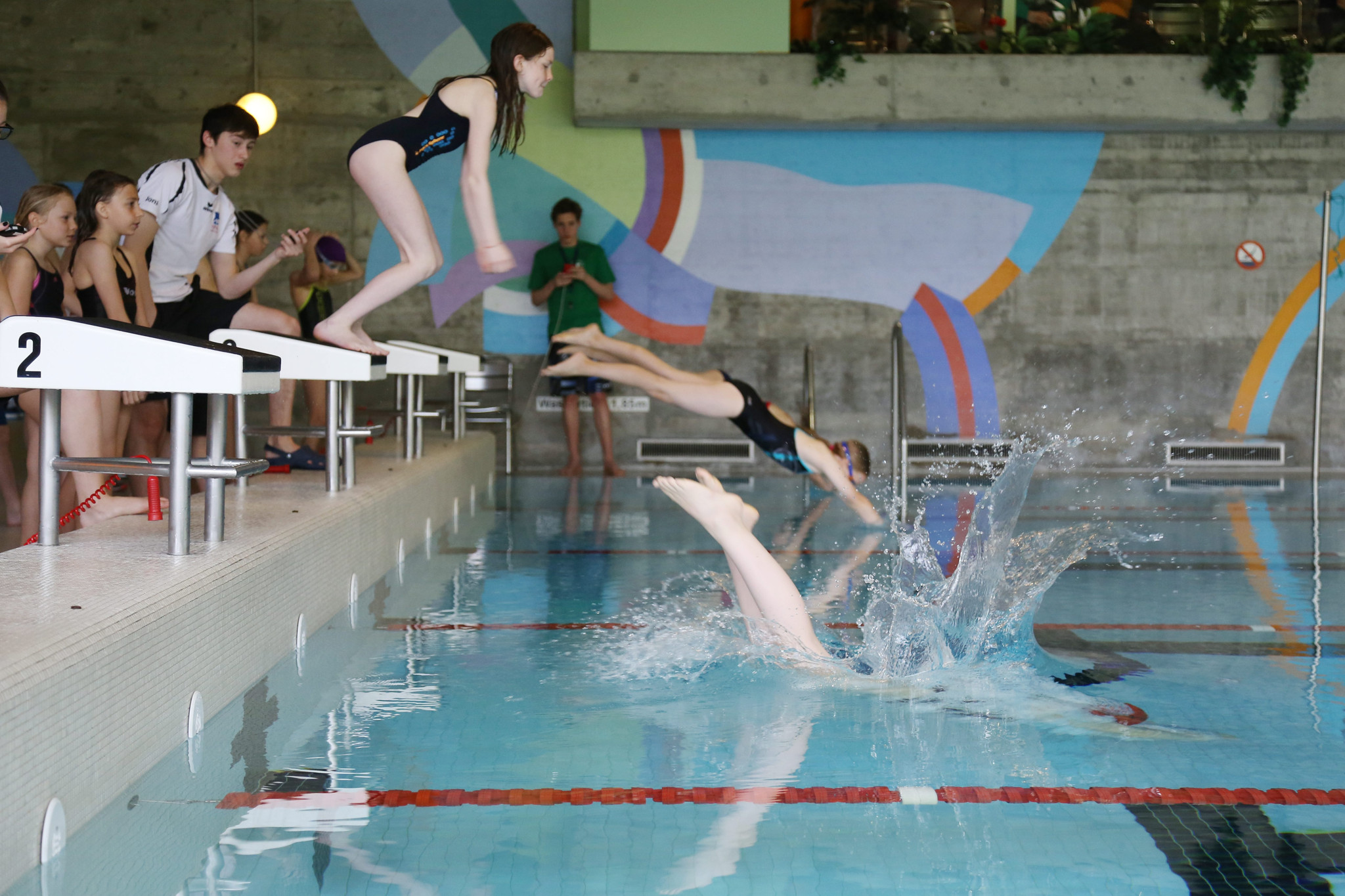 Schülerinnen springen beim Thalwiler Schulschwimmen ins Hallenbad Schweikrüti in Gattikon, während Zuschauer am Beckenrand stehen. Schülerinnen springen beim Thalwiler Schulschwimmen ins Hallenbad Schweikrüti in Gattikon, während Zuschauer am Beckenrand stehen.