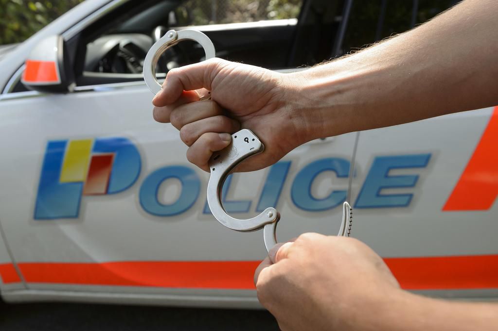 Un policier de la Police cantonale genevoise pose avec des menottes devant une voiture portant le logo de la police, pour des photos d'illustration, ce vendredi 31 juillet 2015 a Geneve. (KEYSTONE/Martial Trezzini) Un policier de la Police cantonale genevoise pose avec des menottes devant une voiture portant le logo de la police, pour des photos d'illustration, ce vendredi 31 juillet 2015 a Geneve. (KEYSTONE/Martial Trezzini)