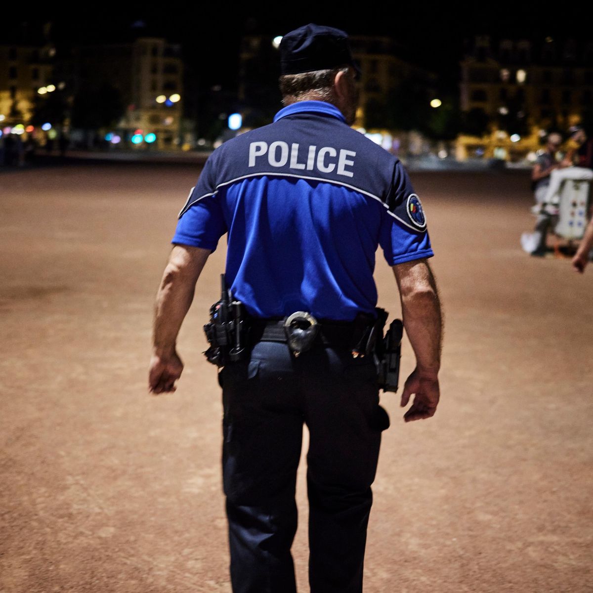 Un policier de la Gendarmerie cantonale patrouille la nuit sur la plaine de Plainpalais à Genève, en réponse aux plaintes sur les nuisances sonores. Photographie par Yvain Genevay.