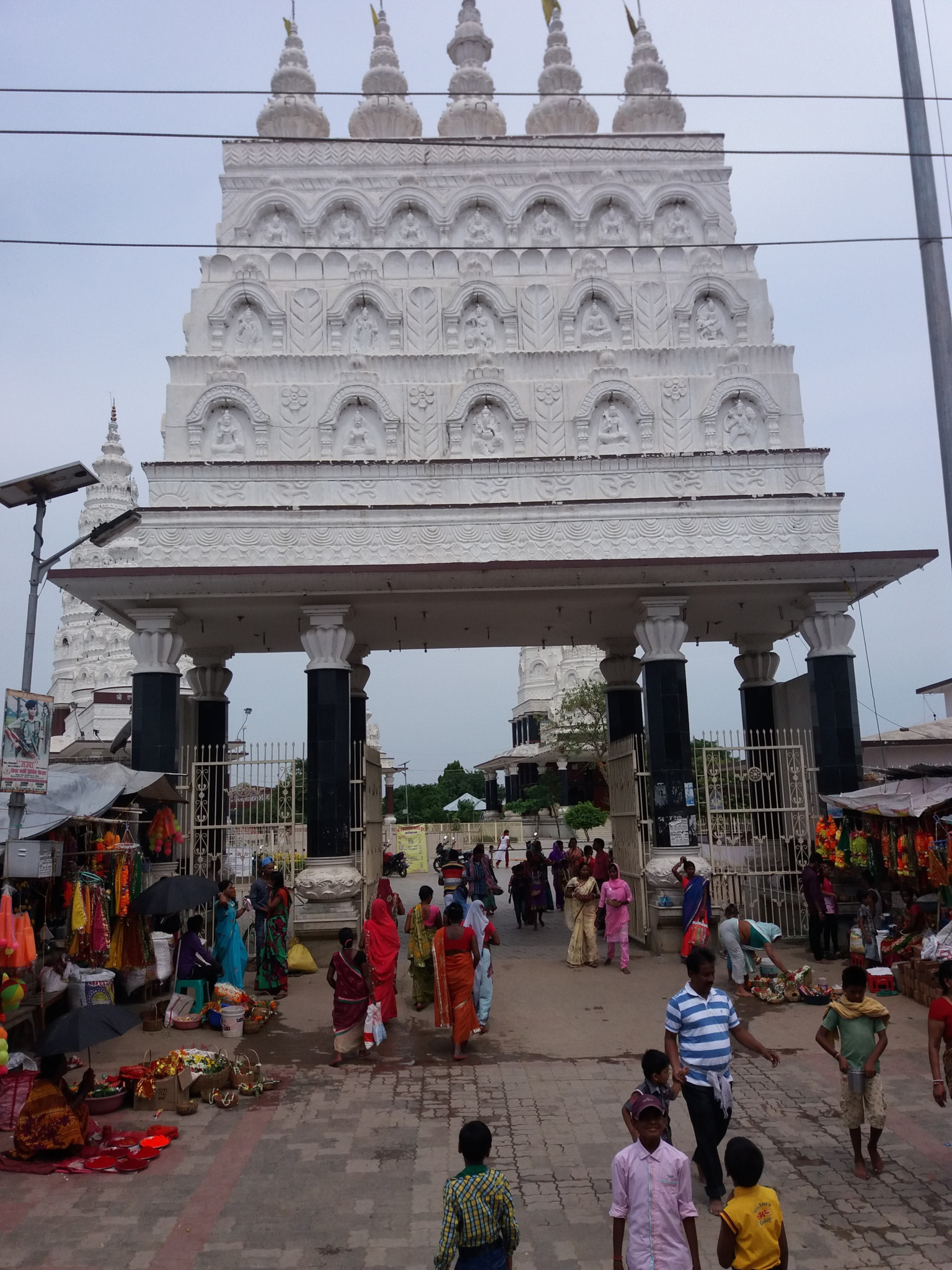 Gläubige Männer und Frauen beim Gebet am Eingangstor des Shiva-Tempels Ashok Dham in Lakhisarai, Indien.
