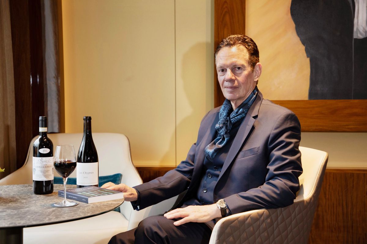 Homme assis à une table avec deux bouteilles de vin et un verre devant lui à l’hôtel Mandarin Oriental, Genève.