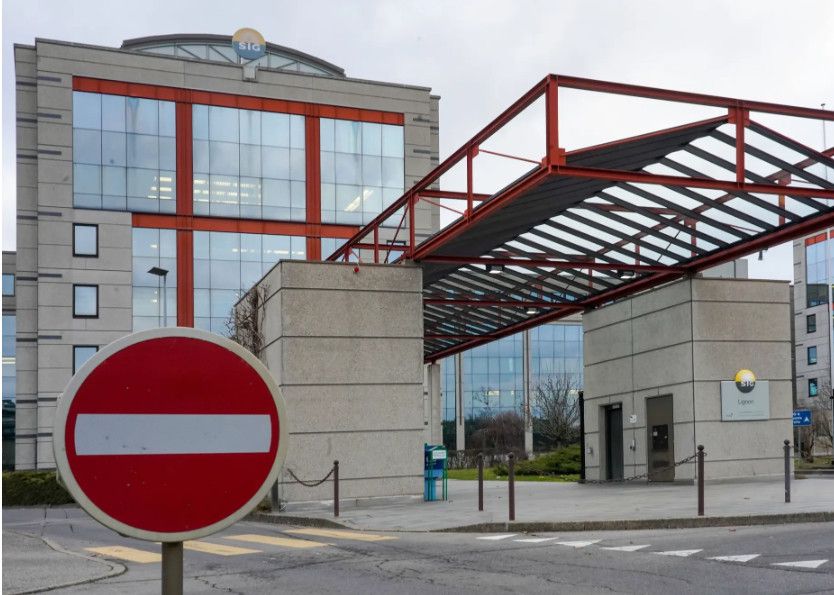 Un panneau de signalisation de sens interdit devant un grand bâtiment moderne avec une structure en acier rouge.