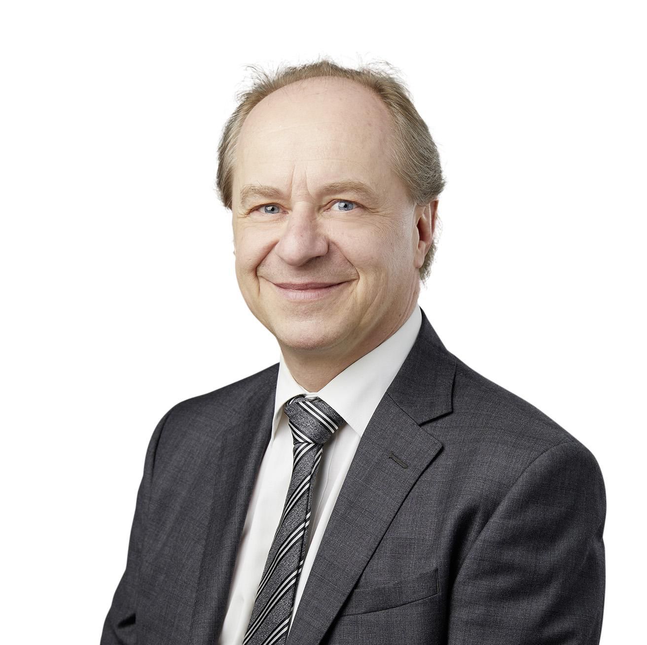 Portrait d’Alain Rebetez, éditorialiste du Matin Dimanche, en costume sombre et cravate rayée.