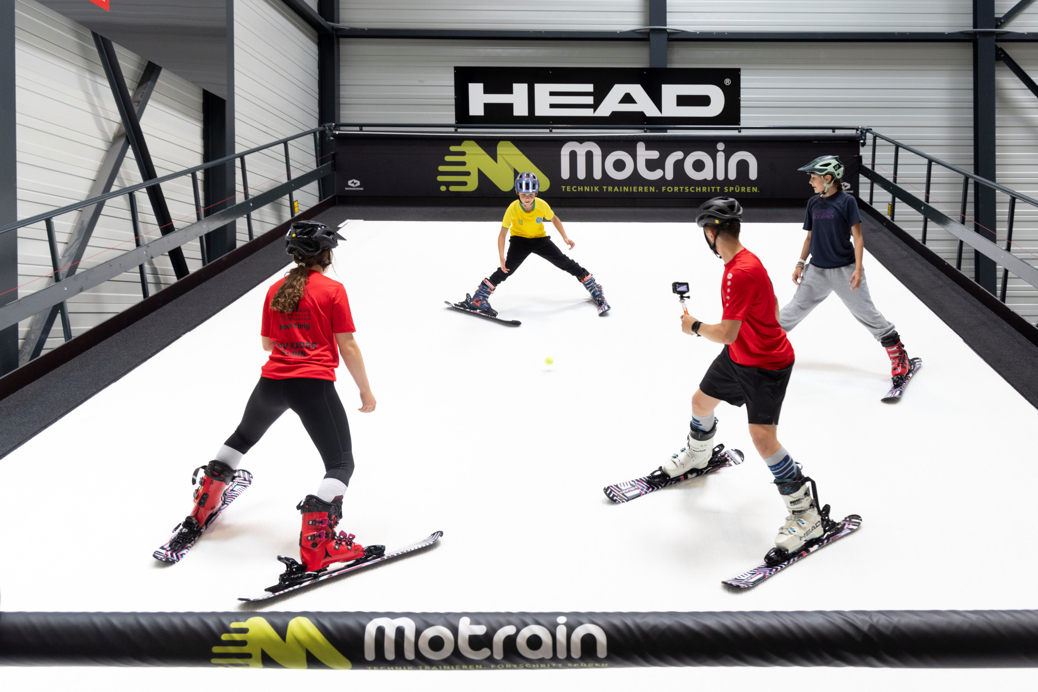 Skifahrende üben in der Motrain-Skihalle in Ennenda auf einem nassen Teppich. Im Hintergrund das HEAD-Logo. Skifahrende üben in der Motrain-Skihalle in Ennenda auf einem nassen Teppich. Im Hintergrund das HEAD-Logo.