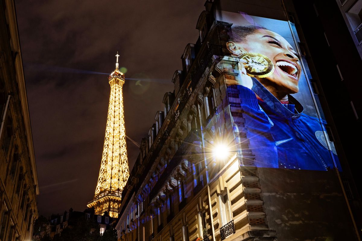 PARIS, FRANCE - AUGUST 03: A photograph of gold medalist Simone Biles of Team United States celebrating on the podium during the medal ceremony for the Artistic Gymnastics Women's Vault Final is projected as part of Parisienne Projections on August 03, 2024 in Paris, France. Parisienne Projections is a Getty Images project which displays the heroes and tragedies of 16 days of Olympic competition throughout the host city of Paris. (Photo by Carmen Mandato/Getty Images)