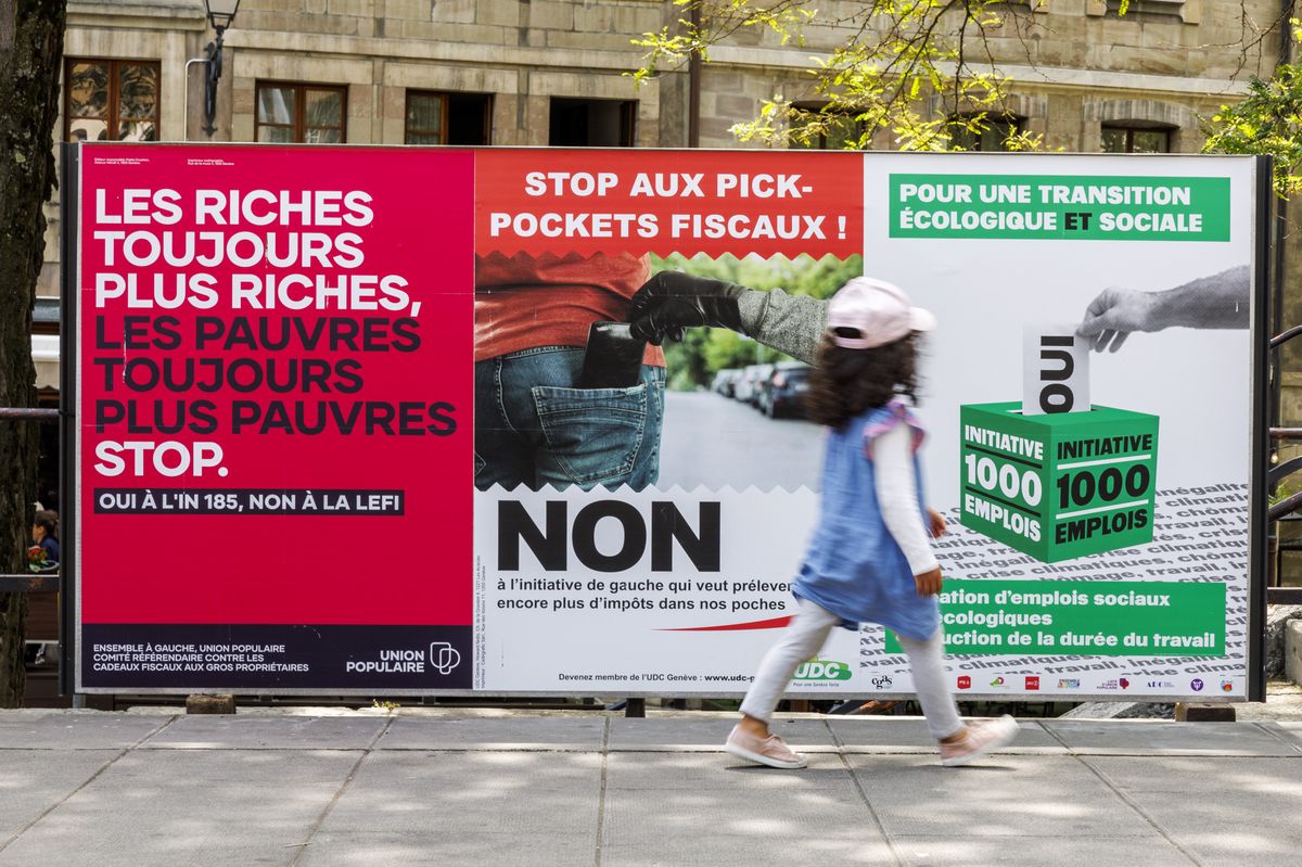 Une petit fille passe devant les affiches des partis politiques et des associations donnant leurs mots d'ordre pour les votations federales, cantonales et communales du 18 juin, ce dimanche 4 juin 2023 a Geneve. Les citoyens suisses et genevois se prononceront sur trois objets federaux: Arrete federal sur une imposition particuliere des grands groupes d'entreprises, Loi sur les objectifs en matiere de protection du climat et sur la Loi federale COVID-19 et des 6 objets cantonaux genevois. (KEYSTONE/Salvatore Di Nolfi)