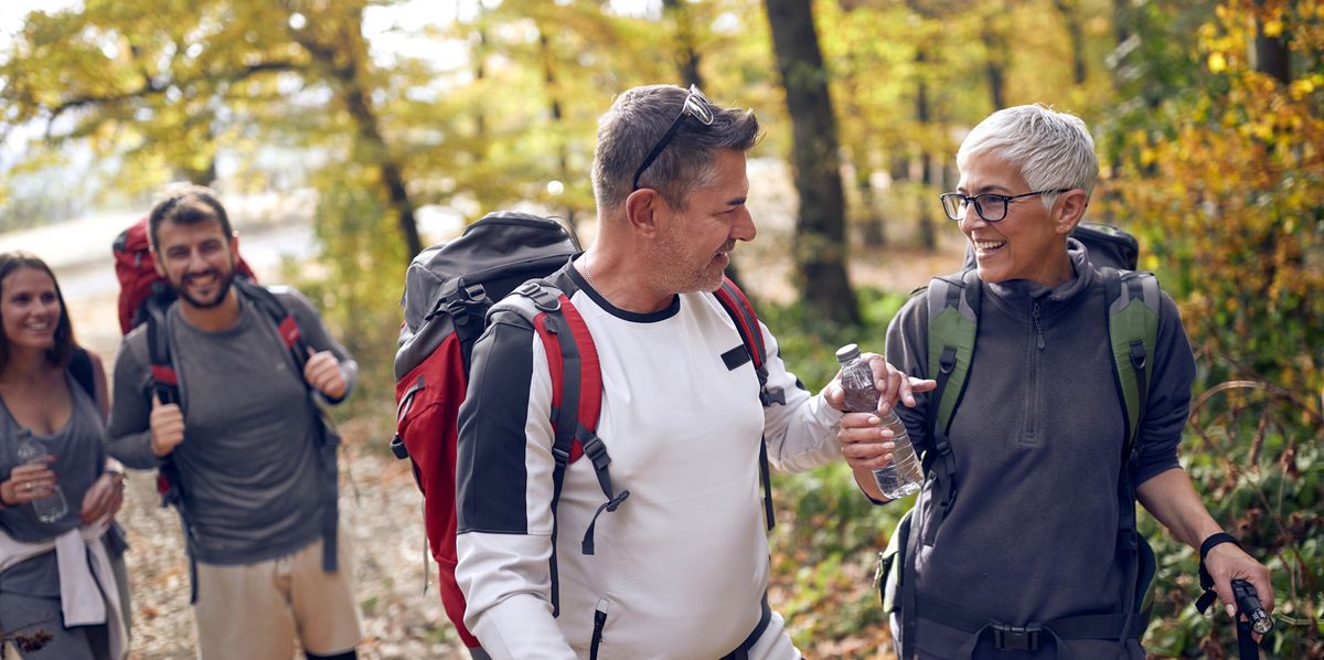 An elderly couple at hiking through the woods getting thirsty