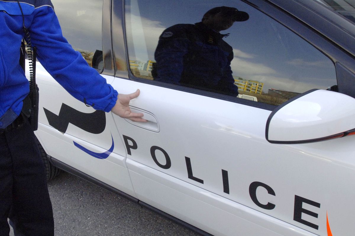 Un policier fribourgeois ouvrant la portière d'une voiture de police avec le nouveau logo lors de la présentation du 13 mars 2006.