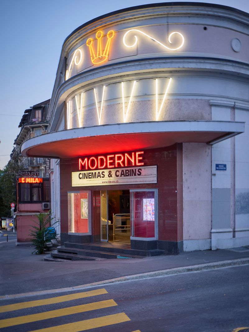 Façade d'un cinéma avec l'inscription 'Moderne, Cinemas & Cabins' et des néons lumineux sur la marquise.