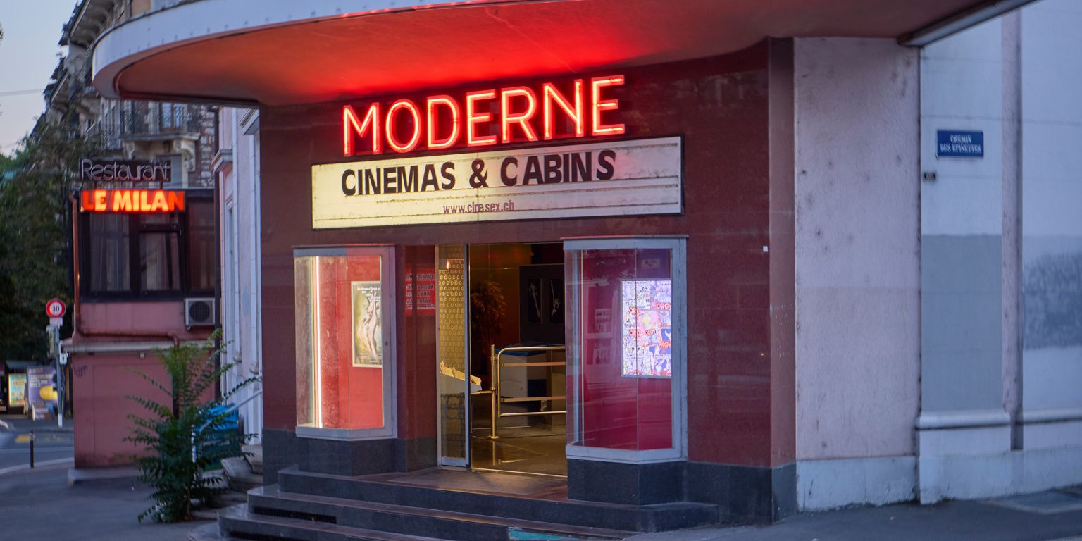 Façade d'un cinéma avec l'inscription 'Moderne, Cinemas & Cabins' et des néons lumineux sur la marquise.