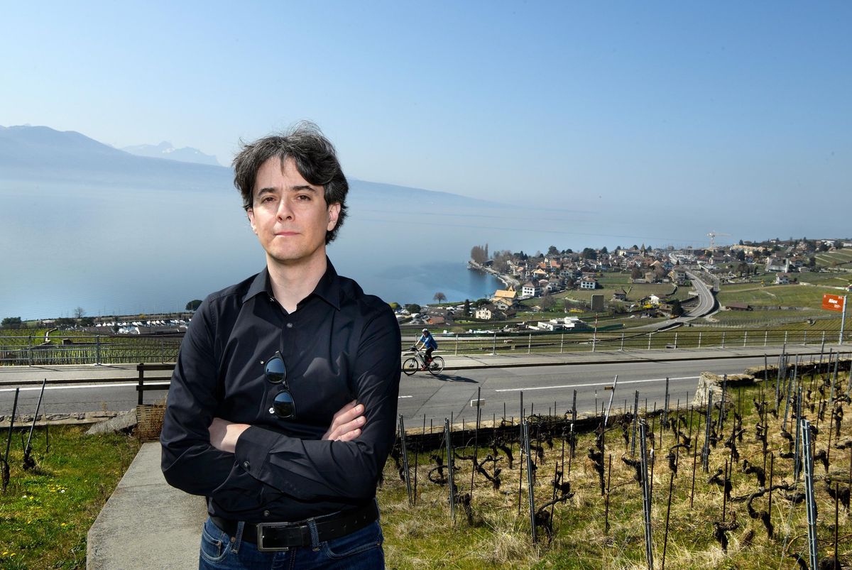 Jean-Christophe Schwaab, vice-syndic de Bourg en Lavaux, pose près d’un vignoble à Riex avec le lac Léman en arrière-plan sous un ciel dégagé.