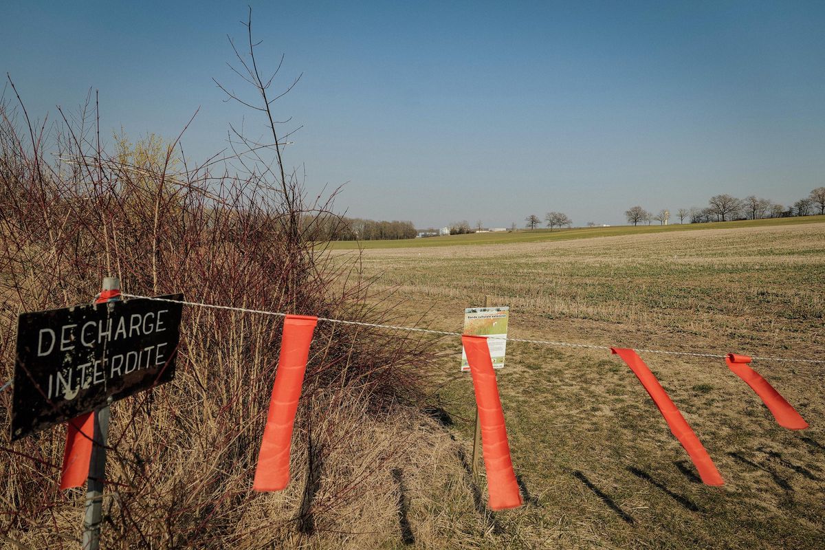 Champ à Satigny avec une pancarte 'Décharge interdite', site du rassemblement contre la décharge des mâchefers, CERN visible en arrière-plan, 6 mars 2022.