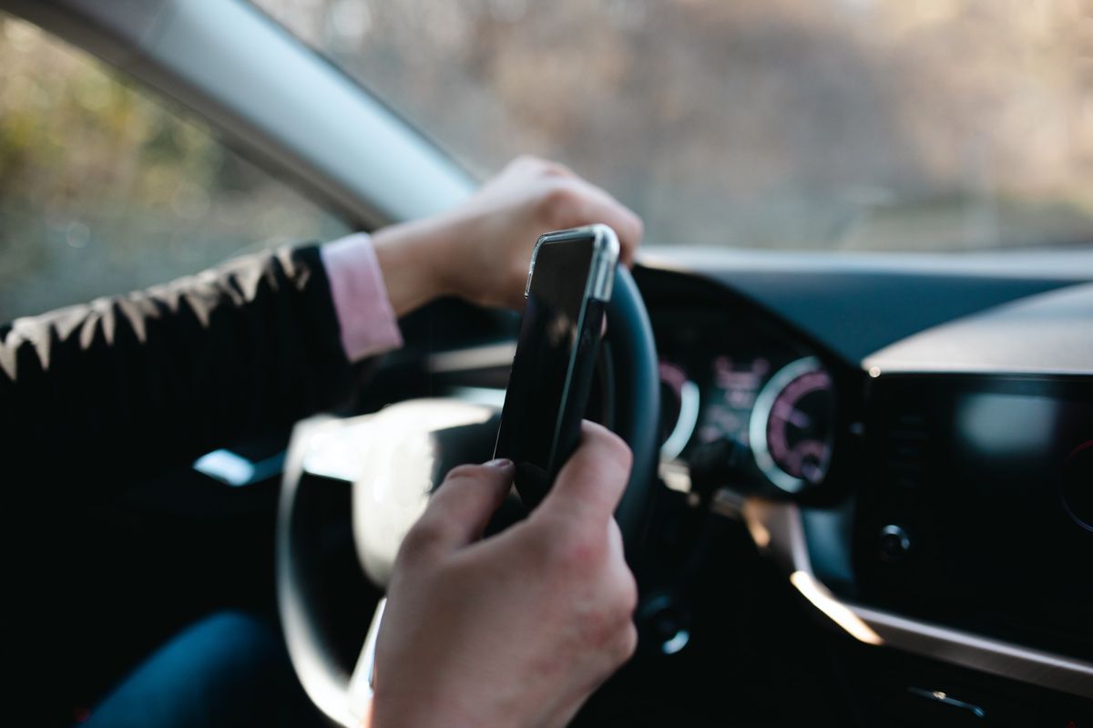 Un homme utilise son téléphone au volant. 