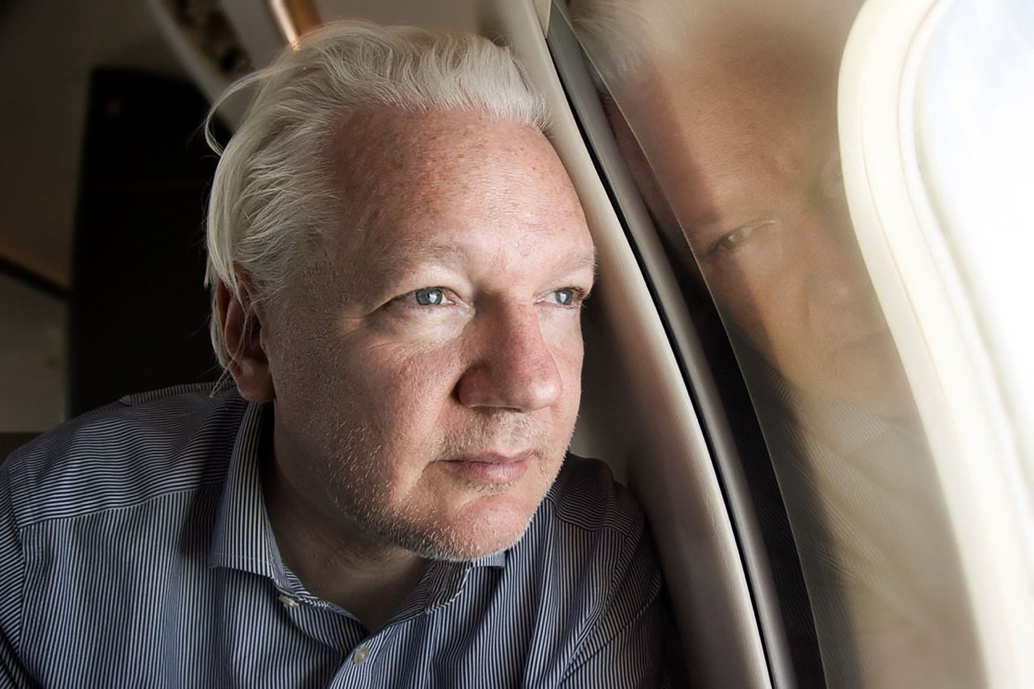 TOPSHOT - This handout courtesy of the WikiLeaks X account @wikileaks posted on June 25, 2024 shows WikiLeaks founder Julian Assange looking out of the window as his plane from London approaches Bangkok for a layover at Don Mueang International Airport in the Thai capital. WikiLeaks founder Julian Assange has been released from prison in Britain and is set to face a final court hearing after reaching a plea deal with US authorities that brings to a close his years-long legal drama. A charter plane flew the 52-year-old from London to Bangkok, where it made a scheduled stop to refuel. (Photo by WikiLeaks / AFP) / -----EDITORS NOTE --- RESTRICTED TO EDITORIAL USE - MANDATORY CREDIT "AFP PHOTO / Courtesy of the WikiLeaks X account @wikileaks  " - NO MARKETING - NO ADVERTISING CAMPAIGNS - DISTRIBUTED AS A SERVICE TO CLIENTS - NO ARCHIVES