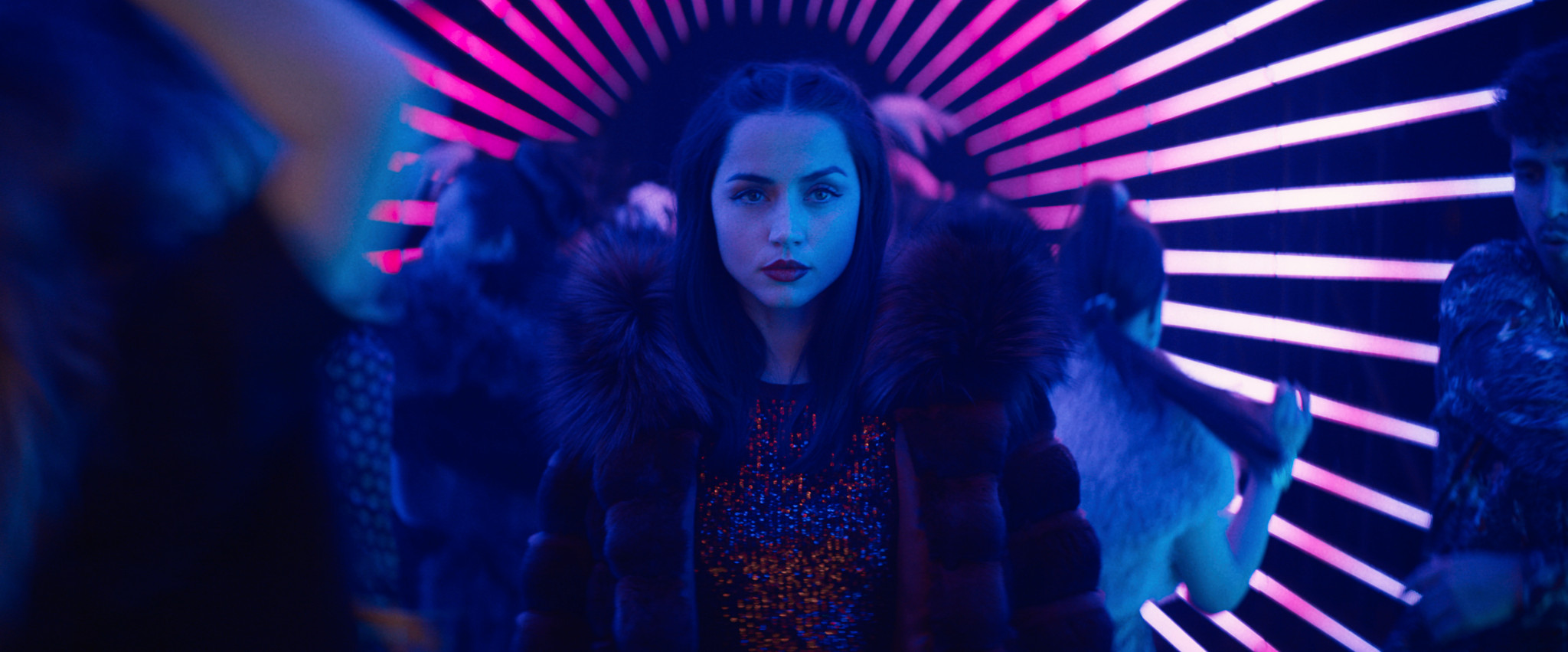 Ana de Armas dans le rôle d’Eve dans Ballerina, entourée de lumières néon colorées.