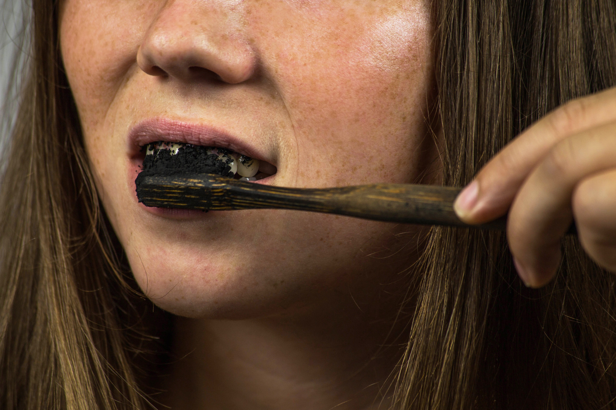 Jeune femme se brossant les dents avec un dentifrice noir au charbon actif et une brosse à dents noire pour le blanchiment dentaire. Jeune femme se brossant les dents avec un dentifrice noir au charbon actif et une brosse à dents noire pour le blanchiment dentaire.