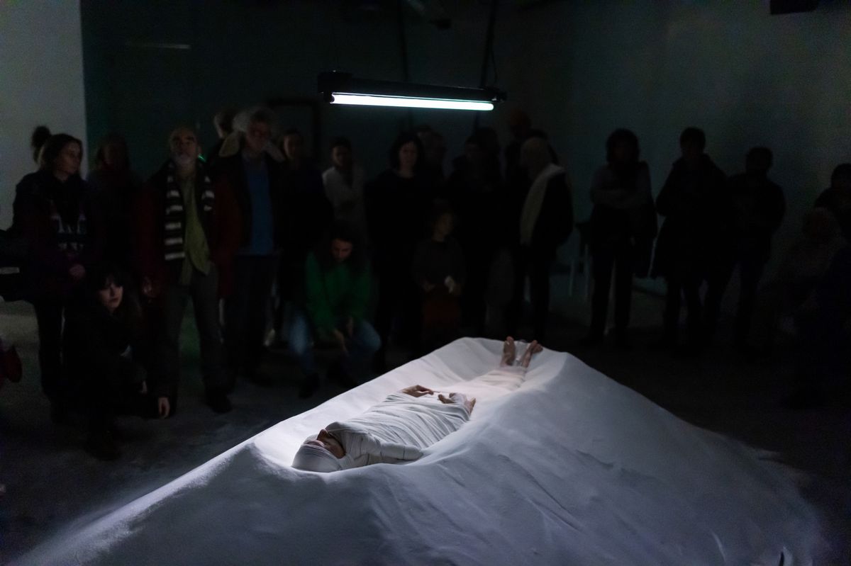 Genève , le 9 décembre 2023.  "Disparitoin": performance de Yann Marussich au Commun. L'artiste propose un réflexion sur l’univers du sucre par le biais de plusieurs disciplines et une approche participative. Ici, l'artiste est allongé sur un monticule-sarcophage de sucre.
Photo Pierre Albouy/Tribune de Genève