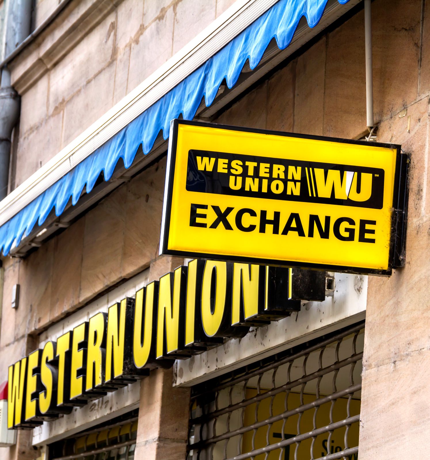 Das leuchtend gelbe Schild einer Western Union Filiale mit der Aufschrift 'Western Union Exchange' an der Vorderseite eines Gebäudes.