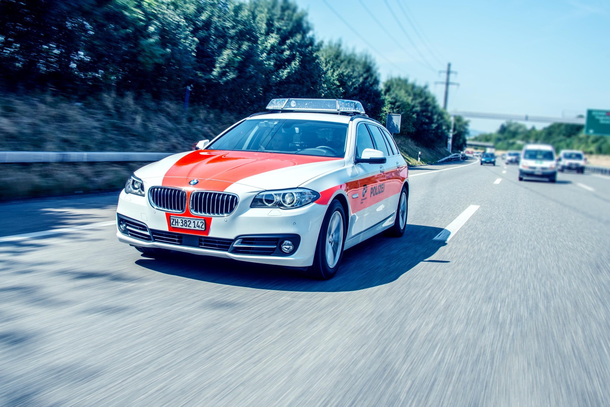 Patrouillenfahrzeug auf Autobahn in Bewegung, Frontansicht, mit blau-weiss-roter Markierung.