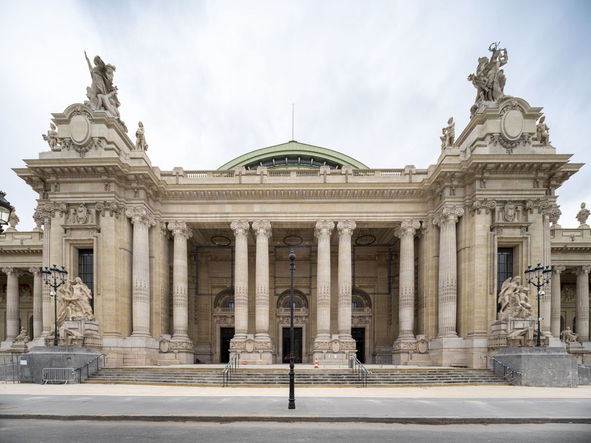 Façade du Palais des Beaux-Arts avec colonnes et statues ornées, sous un ciel nuageux.