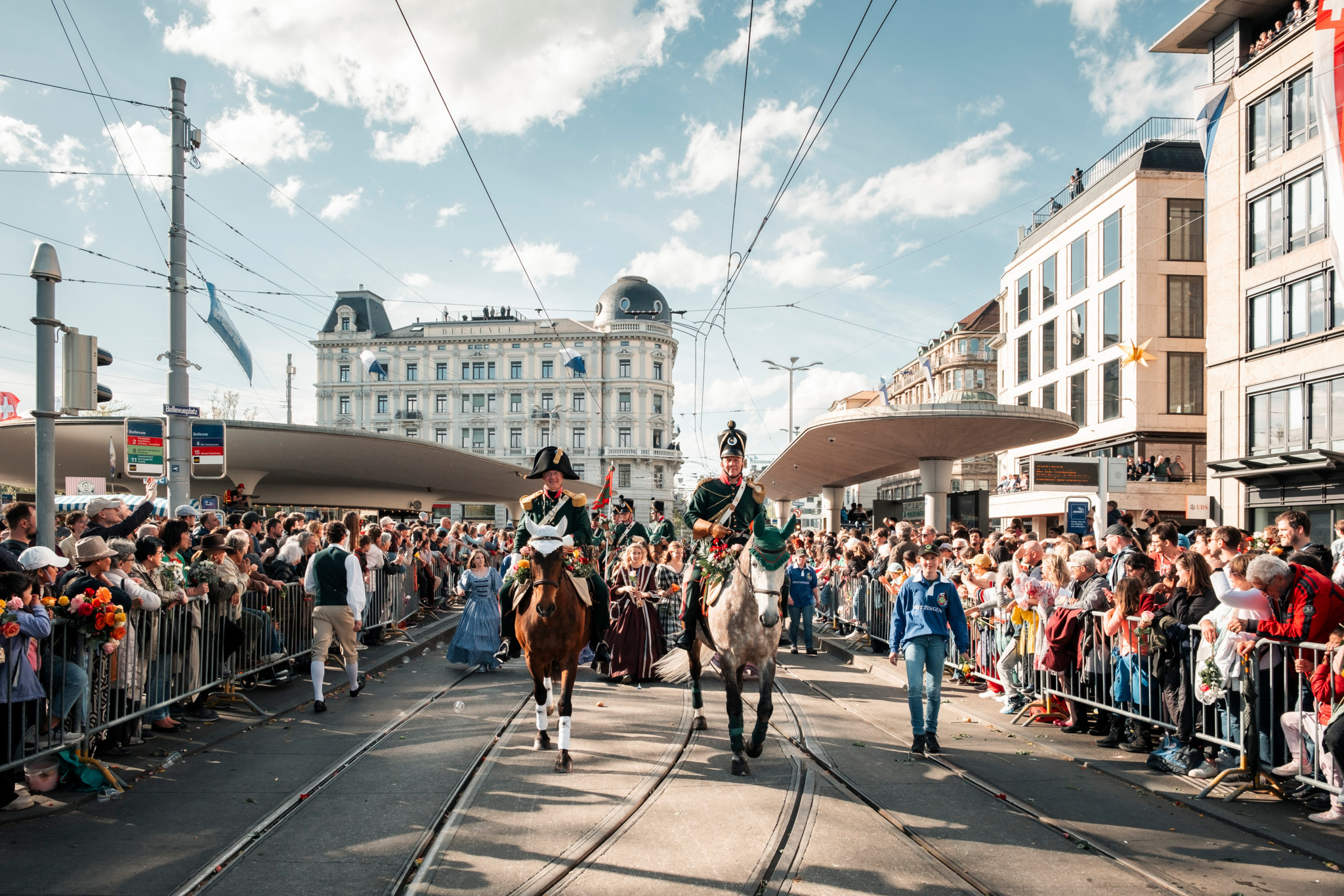 Reiter führen eine Parade am Sechseläuten 2024 in Zürich an, umgeben von jubelnden Zuschauern und historischer Architektur.