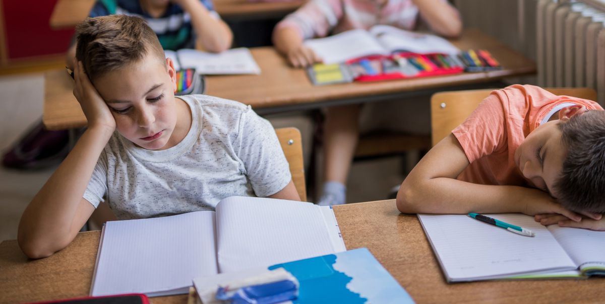 Group of tired school kids feeling bored while sitting in the classroom during the lecture.