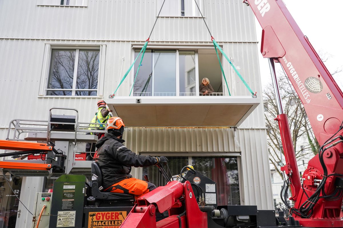 Carouge, le 15/01/2024 -  Pose du premier balcon qui va être clippé sur la façadea d'un des immeubles des Auréas à Carouge dans le quartier de la  Fontenette. Sous les yeux de Mme Bequiri, la locataire dont l'appartement qui reçoit ce premier balcon.
