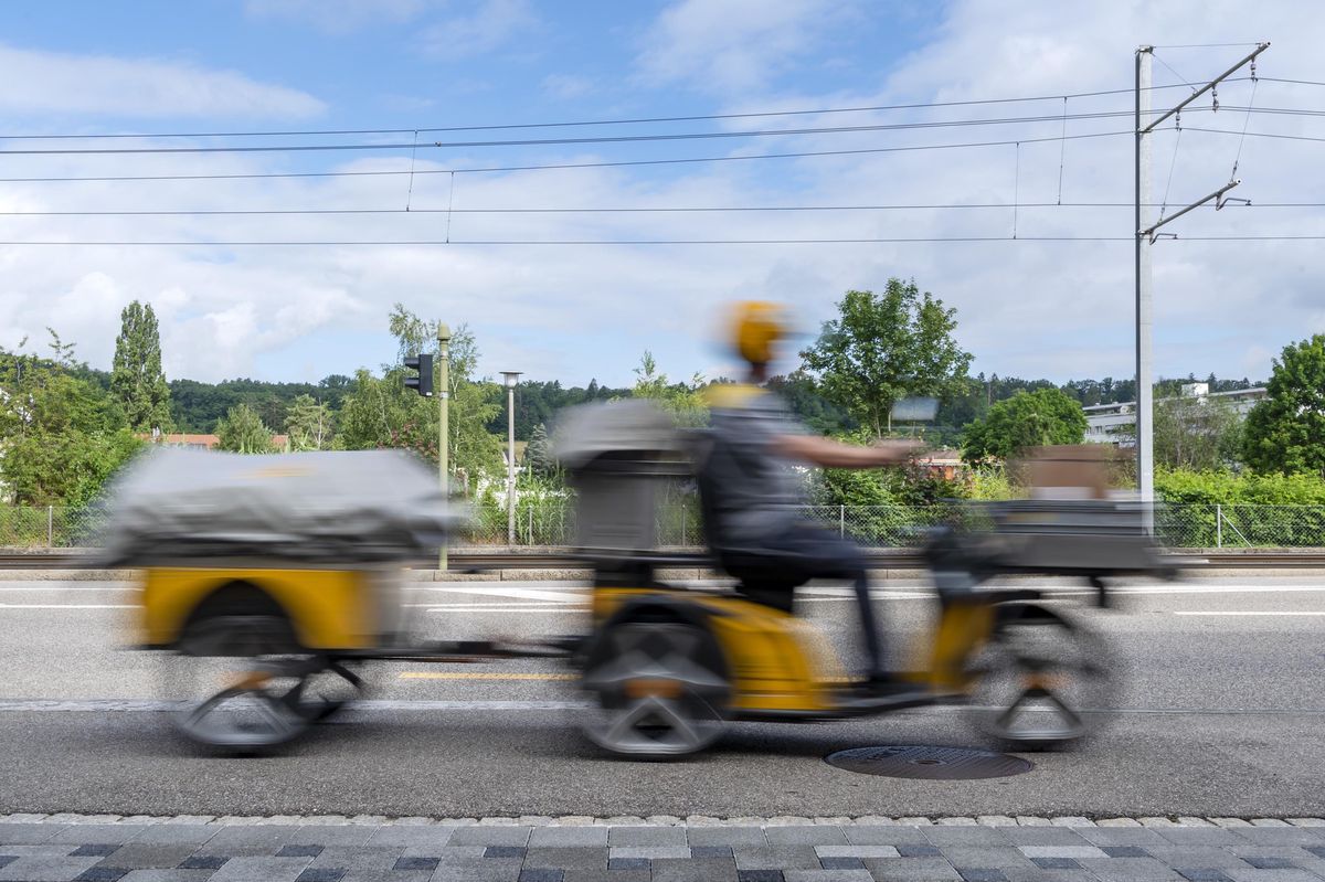 Le facteur roulait au guidon d’un scooter électrique à trois roues, et tirait une remorque, lors de sa tournée dans le sud de Lausanne. (KEYSTONE/Georgios Kefalas)
