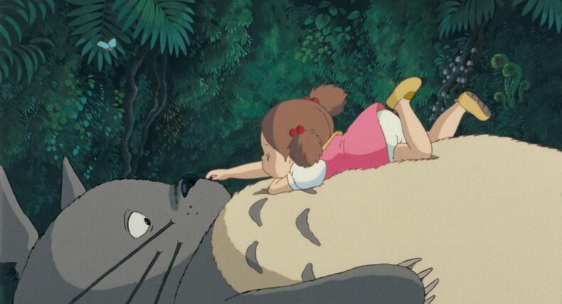 Enfant allongée sur Totoro, une créature géante et pelucheuse, dans une forêt luxuriante.