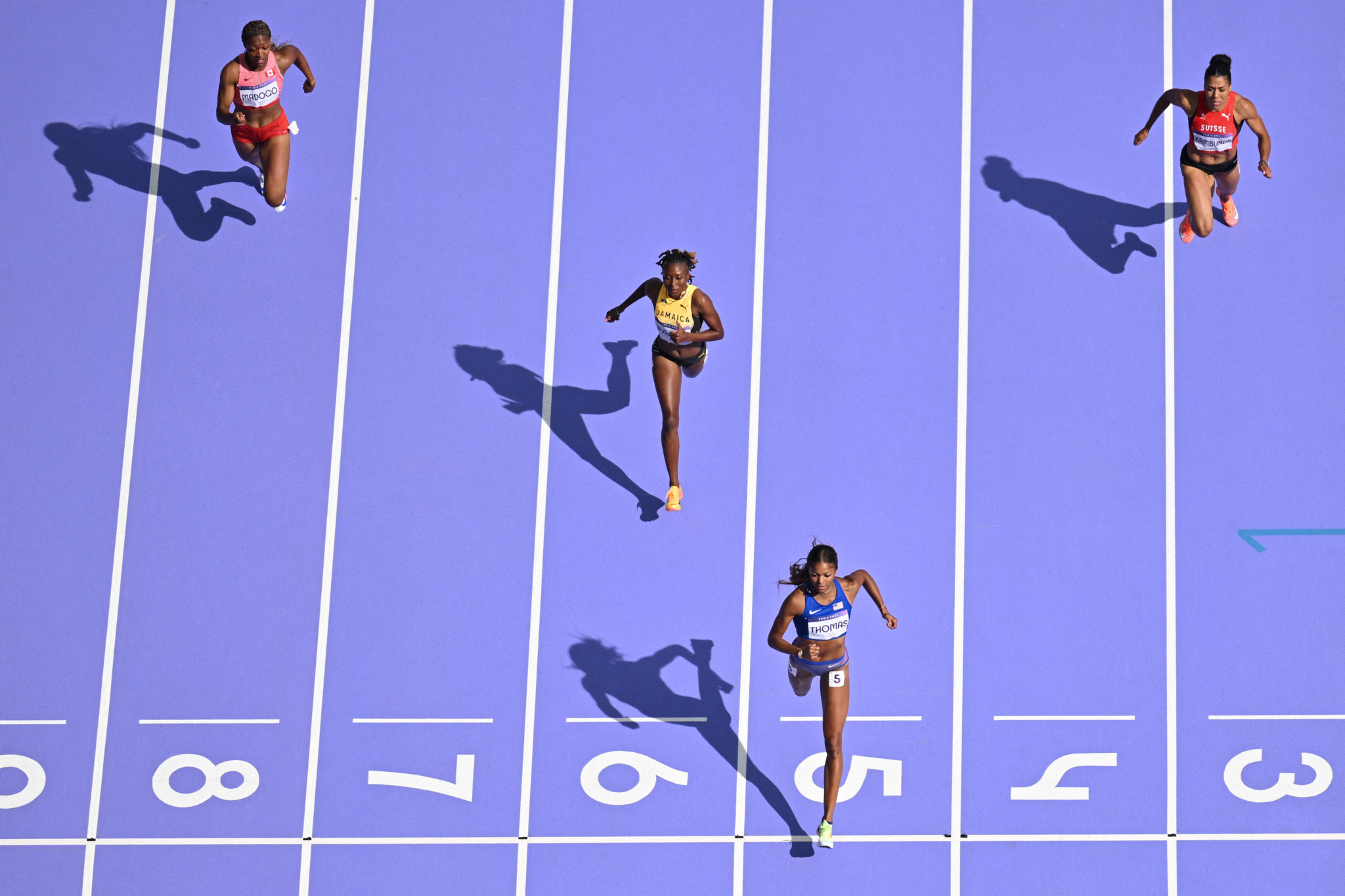 An overview shows US' Gabrielle Thomas (down) crossing the finish line ahead of Jamaica's Niesha Burgher (6), Switzerland's Mujinga Kambundji (3) and Canada's Jacqueline Madogo (8) in the women's 200m heat of the athletics event at the Paris 2024 Olympic Games at Stade de France in Saint-Denis, north of Paris, on August 4, 2024. (Photo by Jewel SAMAD / AFP)