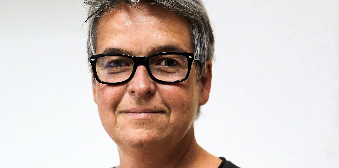 Femme avec des lunettes et cheveux courts, posant devant un fond blanc, Genève, novembre 2014.