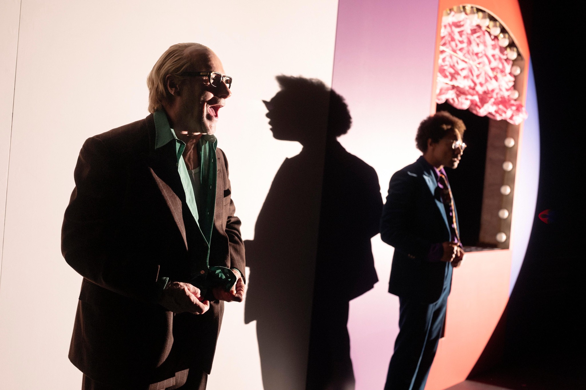 Szenenbild aus ’DIE SCHMUTZIGEN HÄNDE’ von Jean-Paul Sartre am Schauspielhaus Zürich mit zwei Darstellern im Vordergrund und beleuchtetem Hintergrund.