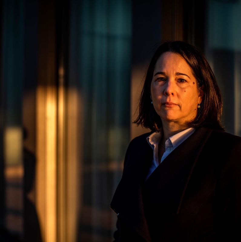 Eine Frau im dunklen Mantel steht vor einem Fenster, warmes Licht fällt auf sie. Sie ist Prof. der juristischen Fakultät Basel und informiert zum Thema sexuelle Belästigung an der Uni Basel.